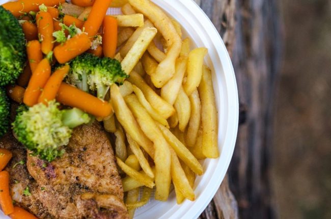 Delicious chicken dinner with broccoli, carrots, and fries on a plate.