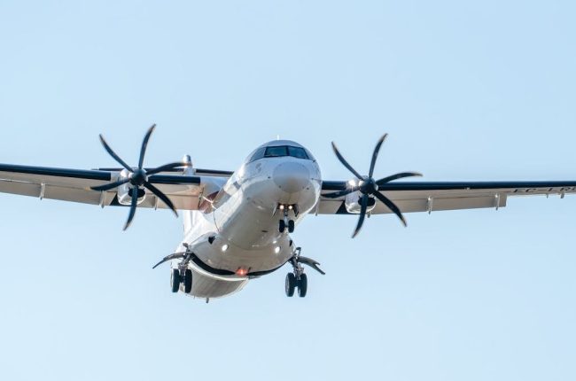 Close-up of an ATR 72 aircraft landing in Manises, Valencia, clear sky background.